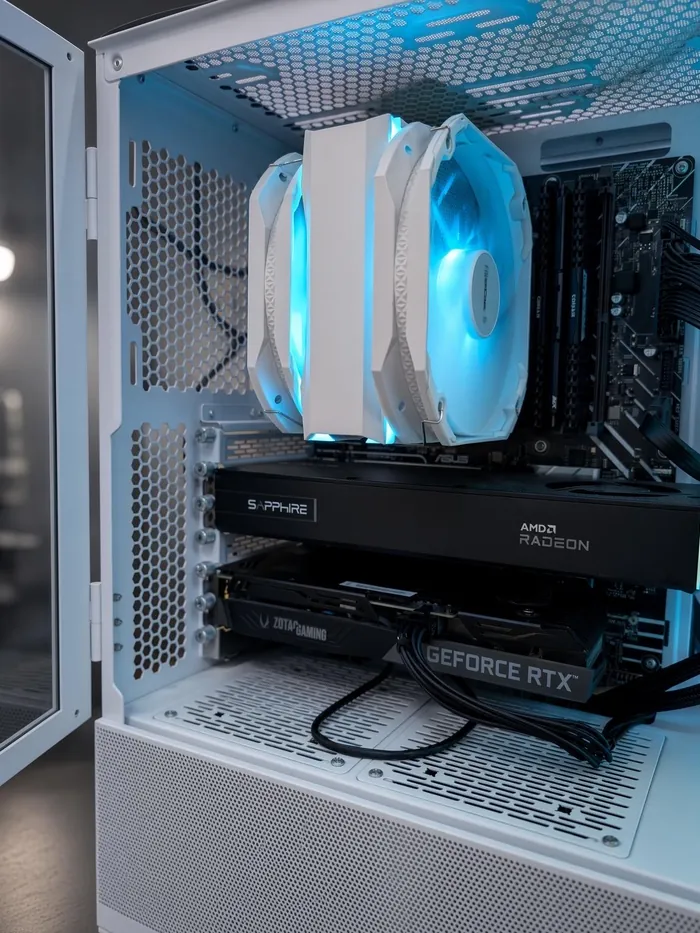 Intérieur d’un boîtier blanc ouvert : un ventirad, une carte graphique Sapphire AMD Radeon et une carte Zotac GeForce RTX montées l’une au-dessus de l’autre.