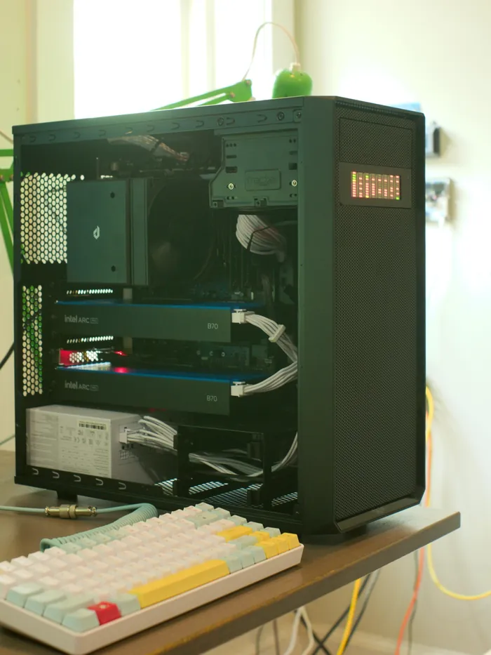 Tour informatique noire ouverte, posée sur un bureau, équipée de deux cartes graphiques professionnelles Intel Arc Pro B70, un clavier au premier plan.